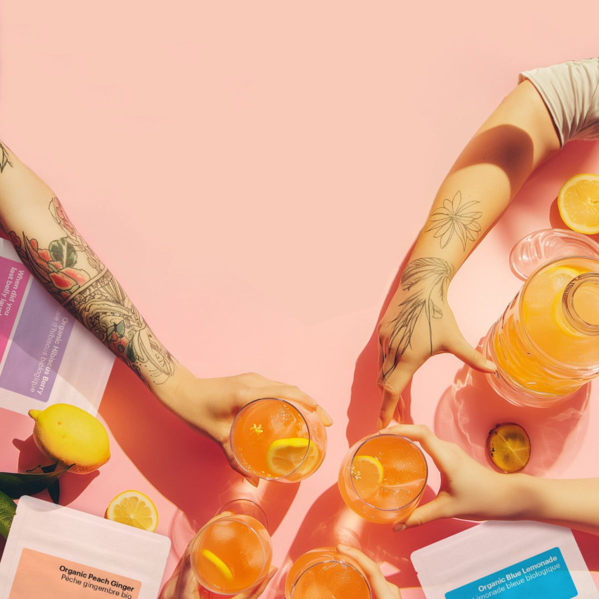 People holding glasses of orange juice with lemons on a pink background